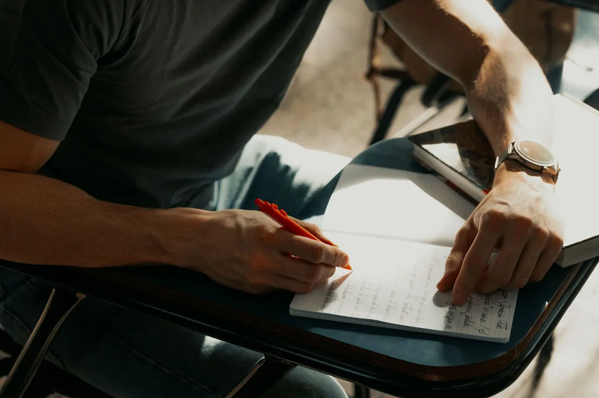 A focused student writing notes in a notebook during class.